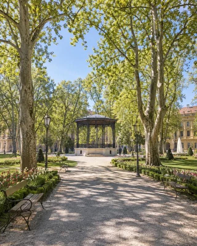 A tree-lined path leads to a bandstand in a European park. Illustrative scene.